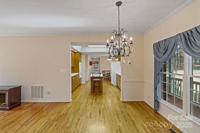 unfurnished dining area featuring a notable chandelier, light wood-type flooring, and crown molding