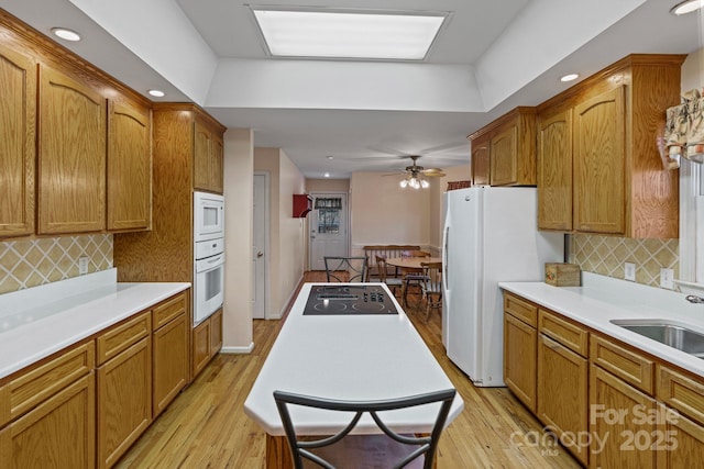 kitchen with light wood-type flooring, sink, backsplash, white appliances, and ceiling fan