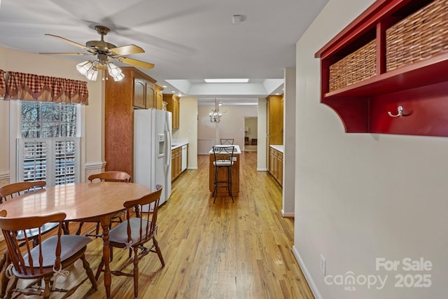 kitchen with ceiling fan with notable chandelier, light wood-type flooring, and white refrigerator with ice dispenser