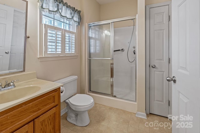 bathroom featuring toilet, tile patterned floors, a shower with shower door, and vanity