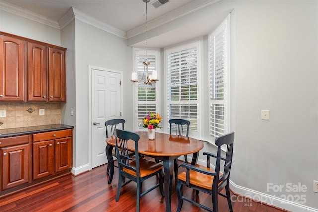 dining room with ornamental molding, a notable chandelier, dark wood finished floors, and baseboards