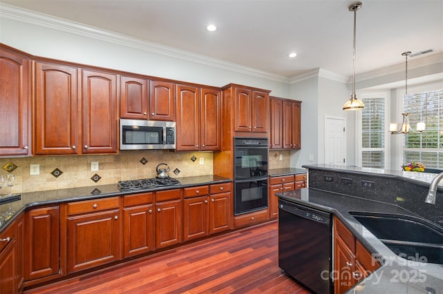 kitchen featuring dark wood-style flooring, a sink, dark stone counters, black appliances, and pendant lighting