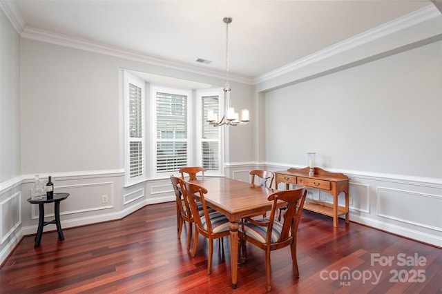 dining room with an inviting chandelier, crown molding, visible vents, and dark wood-style flooring