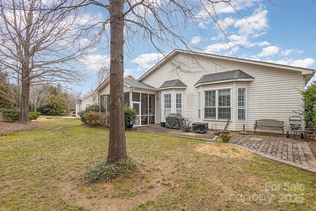 rear view of house featuring a sunroom, a patio area, and a lawn