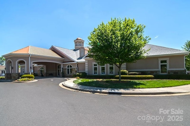 view of front of house featuring driveway, stone siding, and a front yard