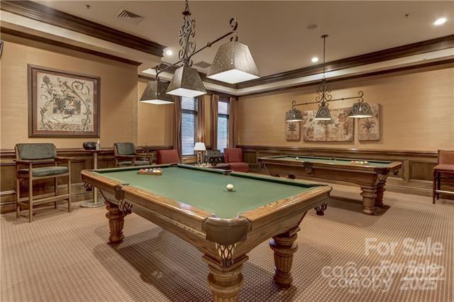 rec room with a wainscoted wall, ornamental molding, visible vents, and light colored carpet