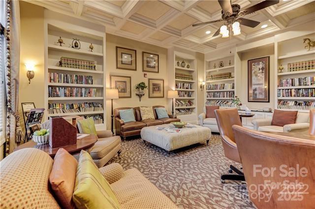 living area featuring ceiling fan, built in shelves, coffered ceiling, and beam ceiling