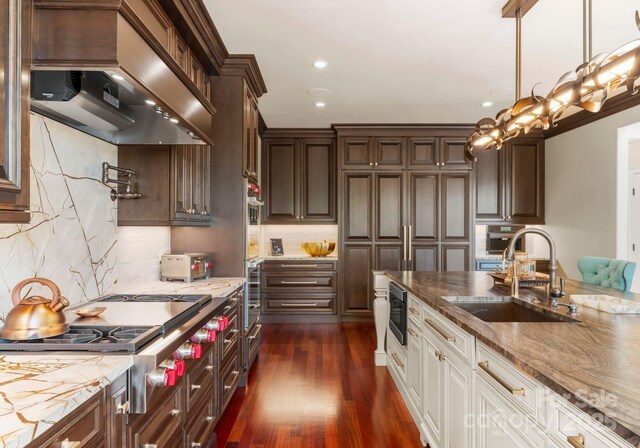 kitchen featuring white cabinetry, appliances with stainless steel finishes, sink, custom exhaust hood, and pendant lighting