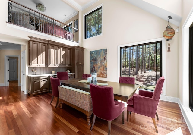 dining room featuring ornamental molding, dark wood-type flooring, and high vaulted ceiling