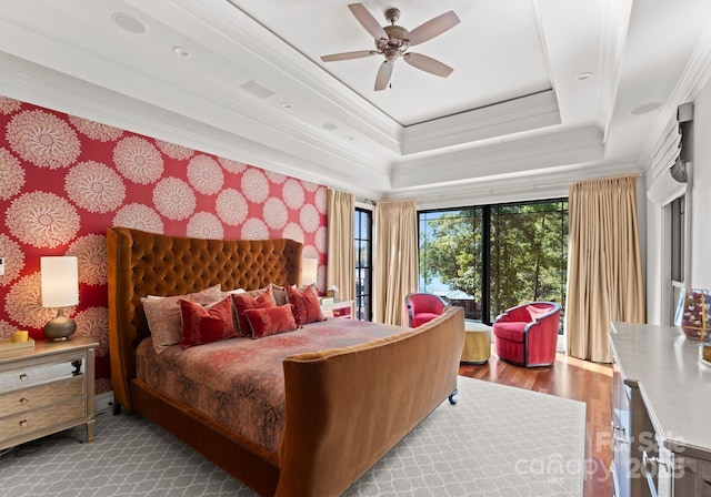 bedroom with a tray ceiling, ceiling fan, crown molding, and light hardwood / wood-style floors