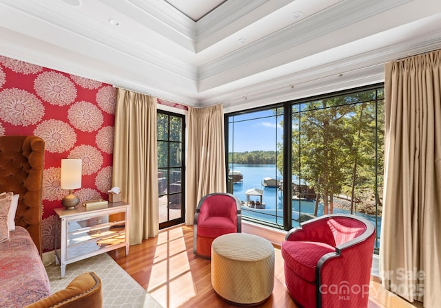 sitting room with crown molding, hardwood / wood-style flooring, and a water view