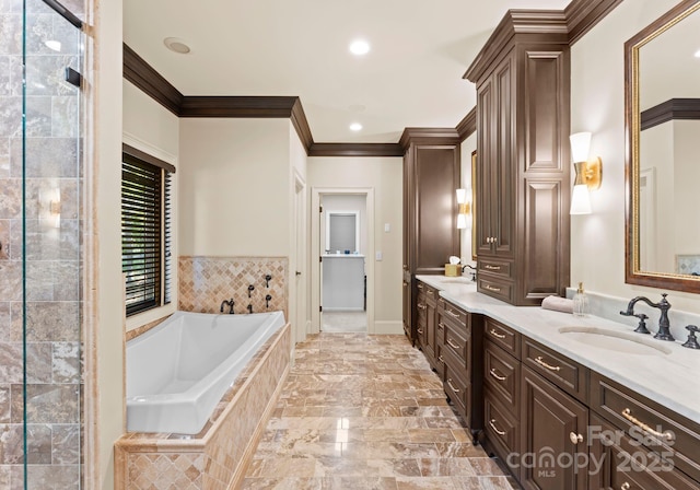 bathroom with ornamental molding, vanity, and tiled tub