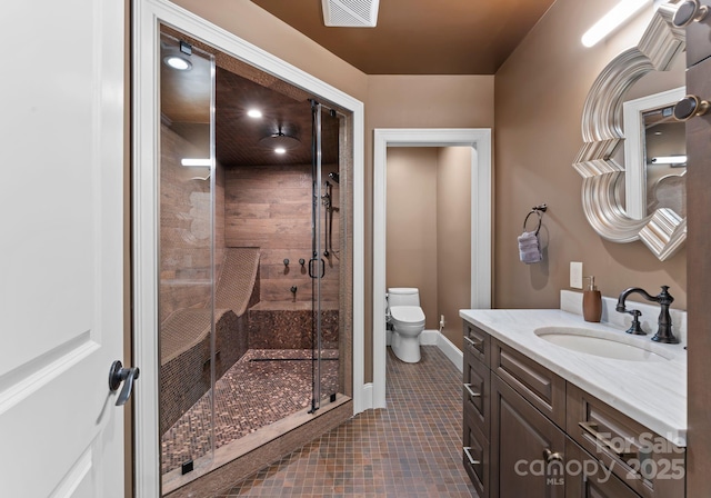 bathroom featuring toilet, tile patterned flooring, an enclosed shower, and vanity