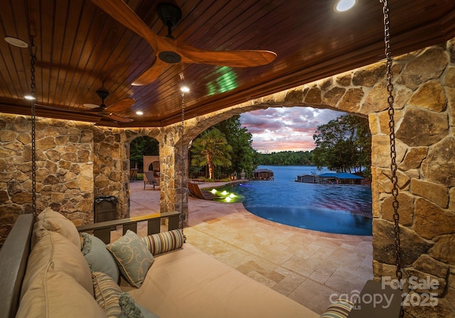 pool at dusk with a patio area and an outdoor living space with a fireplace