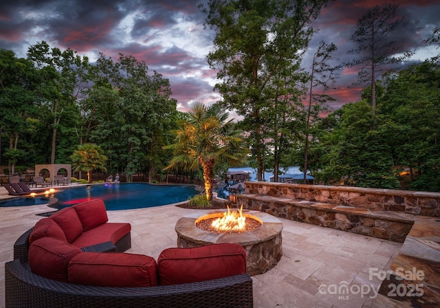 pool at dusk featuring a patio area and a fire pit