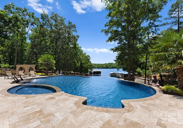 view of pool featuring an in ground hot tub, a patio, and a water view