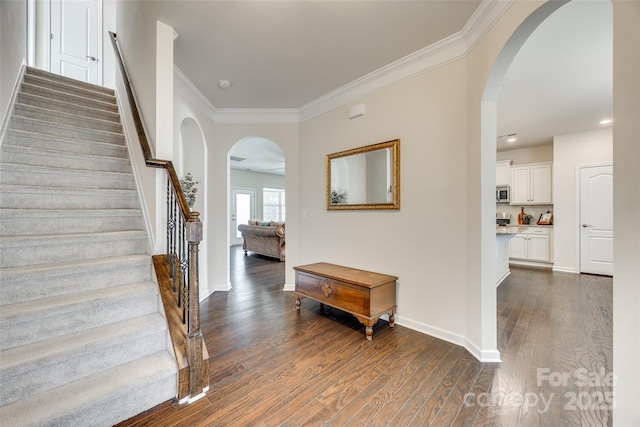 entrance foyer with dark wood-type flooring, arched walkways, and ornamental molding