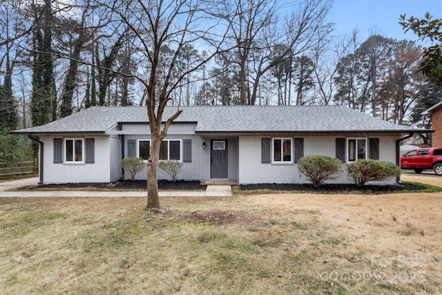 ranch-style home featuring roof with shingles and a front lawn