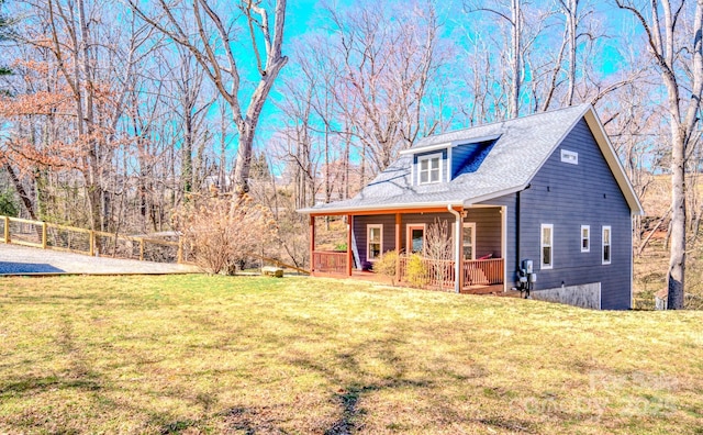 view of front of house featuring a shingled roof, a front yard, covered porch, and fence