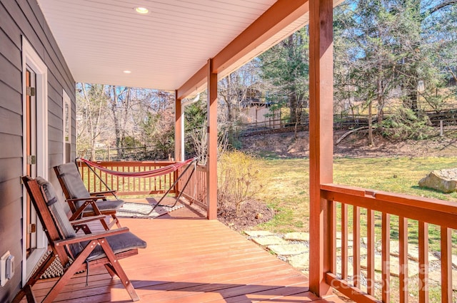 deck with a porch, a lawn, and fence