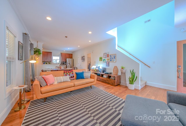 living area featuring light wood-style floors, recessed lighting, visible vents, and ornamental molding