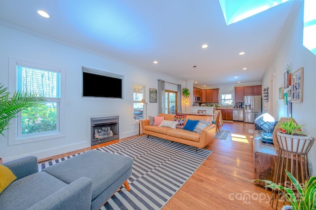 living room with ornamental molding, light wood finished floors, a fireplace, and recessed lighting