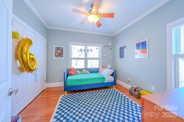 bedroom featuring ornamental molding, multiple windows, light wood-style flooring, and baseboards