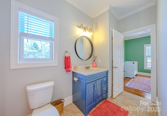 bathroom featuring baseboards, vanity, toilet, and crown molding