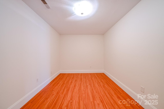 unfurnished room featuring light wood finished floors, visible vents, and baseboards