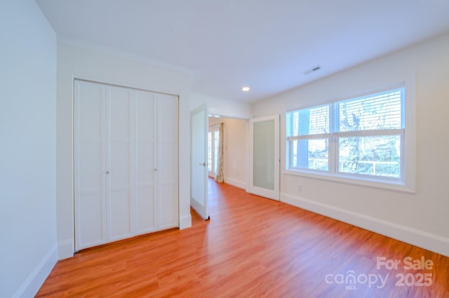 unfurnished bedroom featuring recessed lighting, a closet, visible vents, light wood-style floors, and baseboards