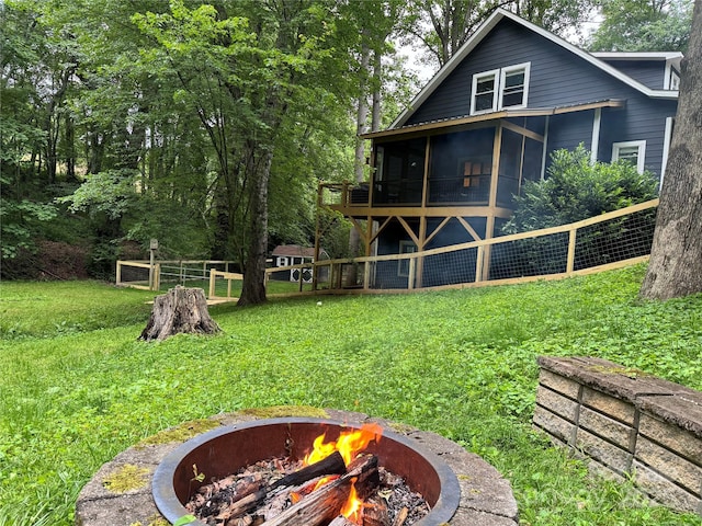 view of yard with a sunroom, fence, and a fire pit