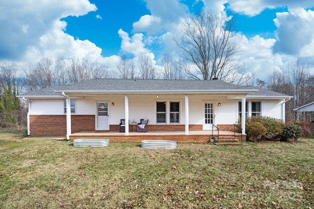 back of property featuring a yard, covered porch, a shingled roof, and brick siding