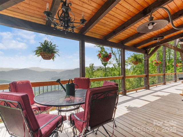 wooden terrace with a mountain view, a ceiling fan, and outdoor dining space