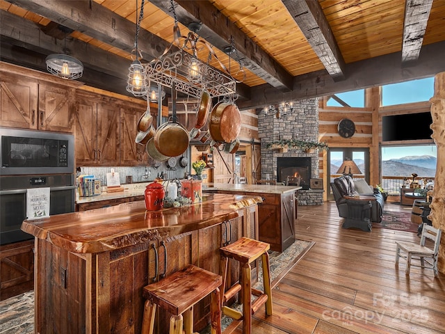 kitchen featuring wall oven, wood ceiling, a kitchen island, and black microwave