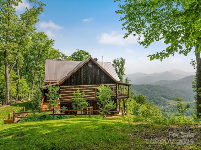 rear view of house featuring a mountain view, metal roof, and a yard