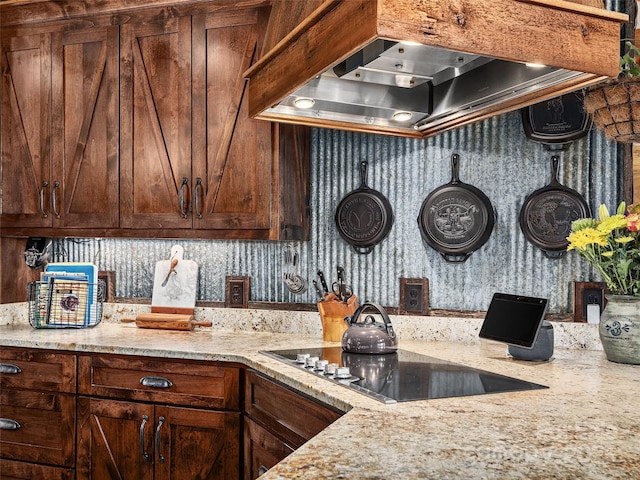 kitchen with light stone countertops, wall chimney exhaust hood, and black electric cooktop