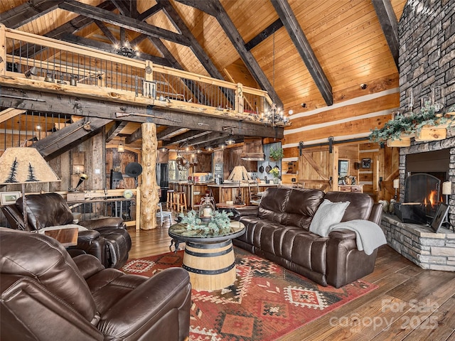 living area with hardwood / wood-style flooring, a barn door, a fireplace, and wood walls