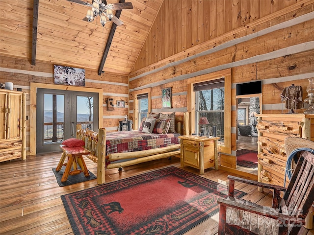 bedroom with hardwood / wood-style flooring, wooden walls, and multiple windows