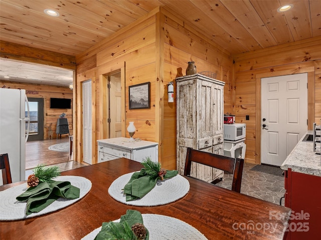 dining room featuring wood ceiling and wooden walls