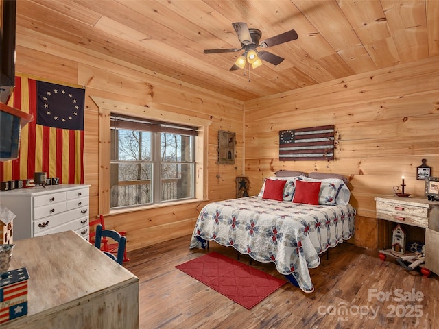 bedroom featuring a ceiling fan, wood ceiling, wood walls, and wood finished floors