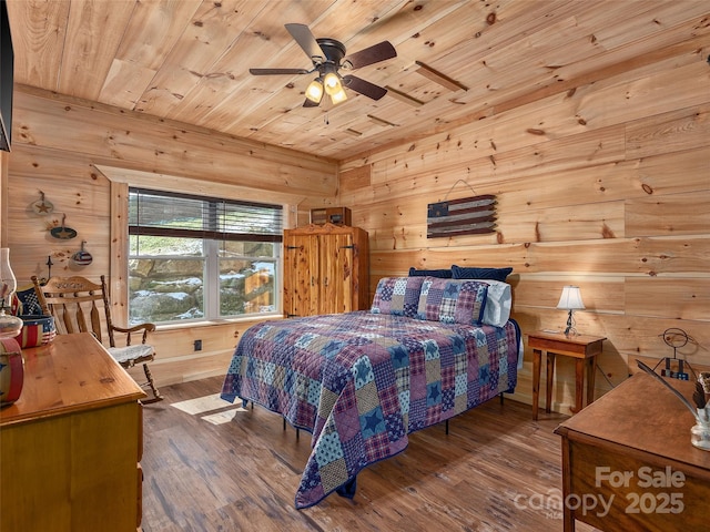 bedroom with ceiling fan, wooden ceiling, wood finished floors, and wooden walls