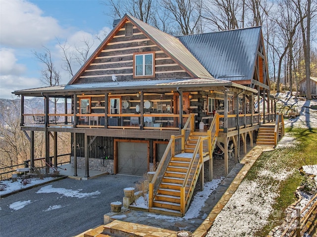 view of front facade featuring a porch, metal roof, an attached garage, and stairs