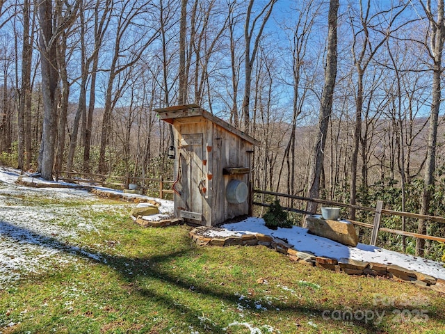 view of shed featuring a forest view and fence