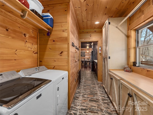 laundry room featuring wooden ceiling, cabinet space, washer and dryer, and wood walls