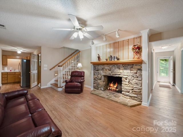 2988 Parks Lafferty Rd, Concord, NC 28025 - living area with a ceiling fan, light wood-style floors, a textured ceiling, a fireplace, and rail lighting