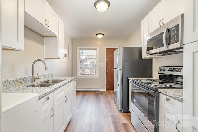 kitchen with appliances with stainless steel finishes, sink, white cabinetry, and light stone countertops