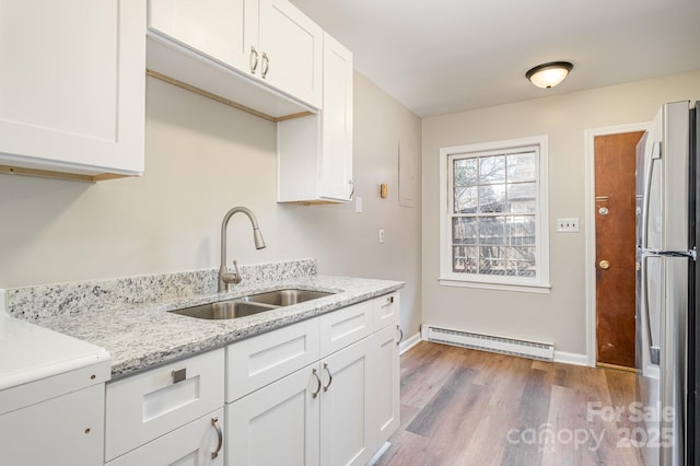 kitchen featuring a baseboard radiator, white cabinets, stainless steel refrigerator, hardwood / wood-style floors, and sink