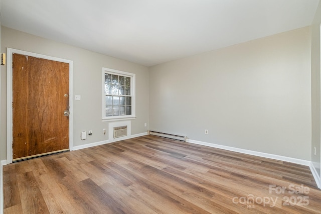 unfurnished room with light hardwood / wood-style flooring, a wall mounted AC, and a baseboard radiator