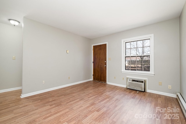 unfurnished room featuring a baseboard heating unit, a wall mounted air conditioner, and light hardwood / wood-style floors