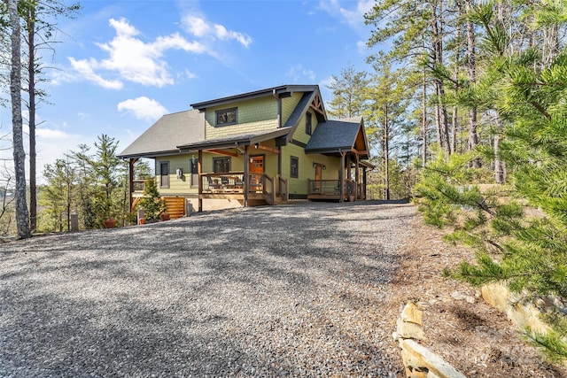 view of front of property featuring driveway, a porch, and a shingled roof